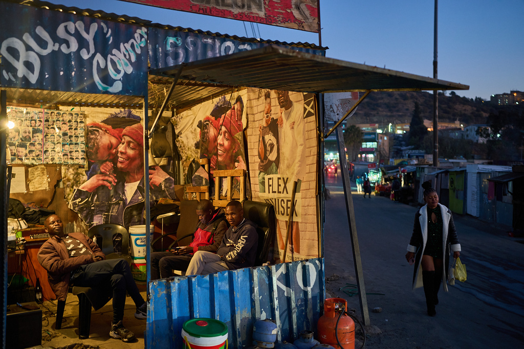 FILE - A woman passes a barber shop at the end of the day in Maseru, Lesotho, July 18, 2025. (AP Photo/Bram Janssen, File)