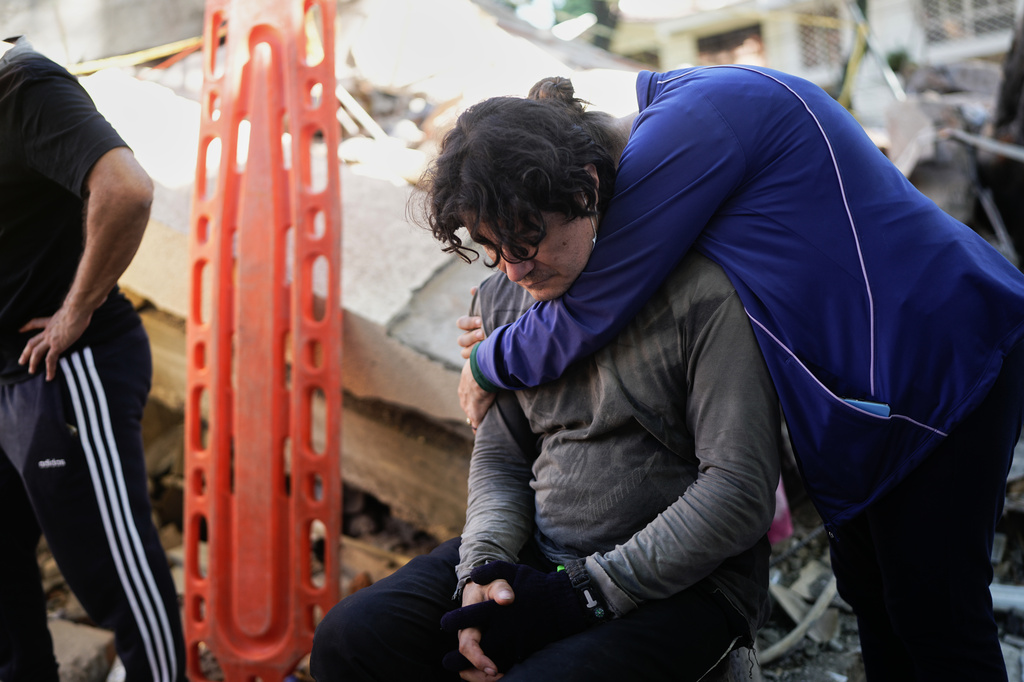 Neighbors embrace as rescue workers search through the rubble of a collapsed apartment building the day after an earthquake struck Cali, Colombia, Tuesday, Aug. 11, 2026. (AP Photo/Ivan Valencia)
