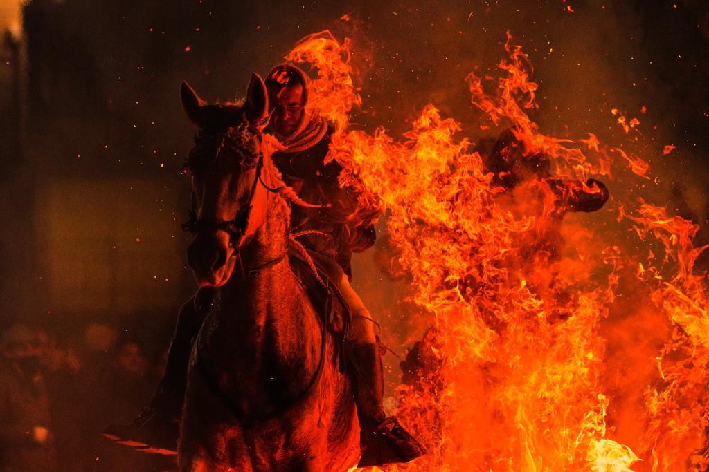 A man rides a horse through a bonfire as part of a ritual in honor of Saint Anthony the Abbot, the patron saint of domestic animals, in San Bartolome de Pinares, Spain, Friday, Jan. 16, 2026. (AP Photo/Manu Fernandez)