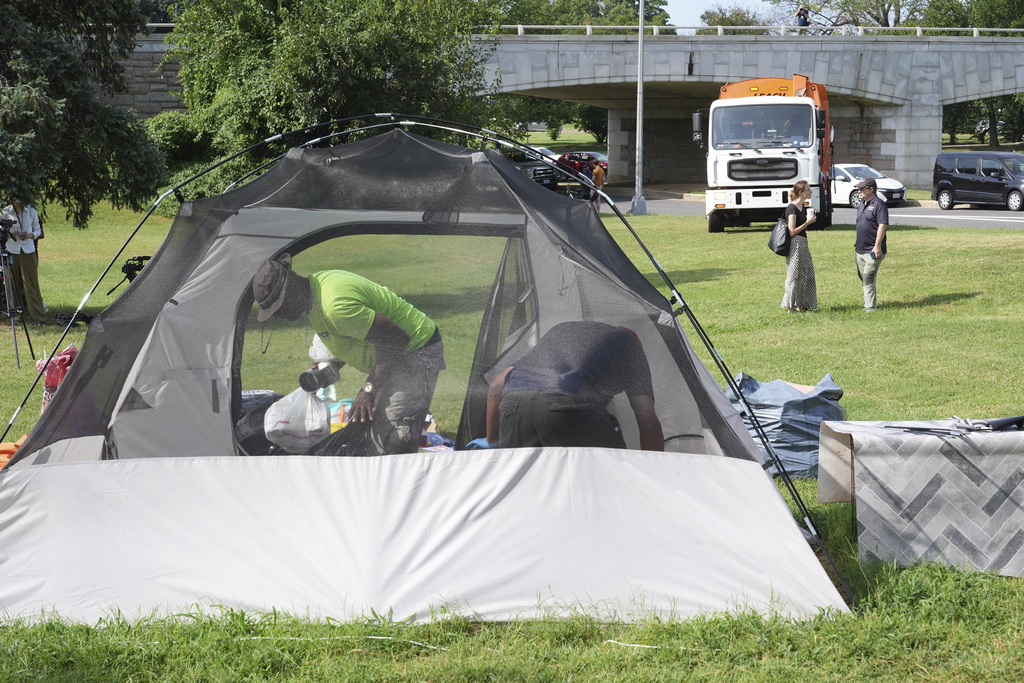 Garbage trucks wait as the homeless empty their belongs from their tents, Thursday, Aug. 14, 2025, in Washington. (AP Photo/Jacquelyn Martin)
