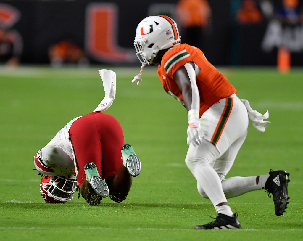 Louisville linebacker T.J.Capers, left, intercepts a pass intended for Miami tight end Elija Lofton, right, during the second half of an NCAA college football game, Friday, Oct. 17, 2025, in Miami Gardens, Fla. (AP Photo/Michael Laughlin)