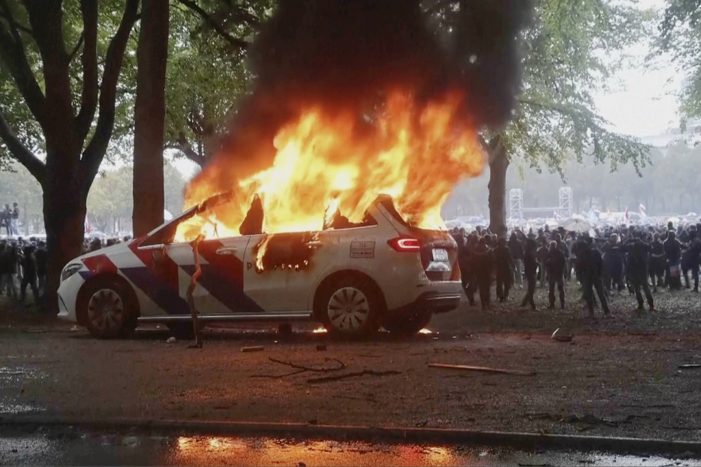 A police vehicle burns as a right-wing demonstration erupted into violence and chaos as rioters clashed with police on Saturday, Sept. 20, 2025 in The Hague, Netherlands. (REGIO8 via AP)