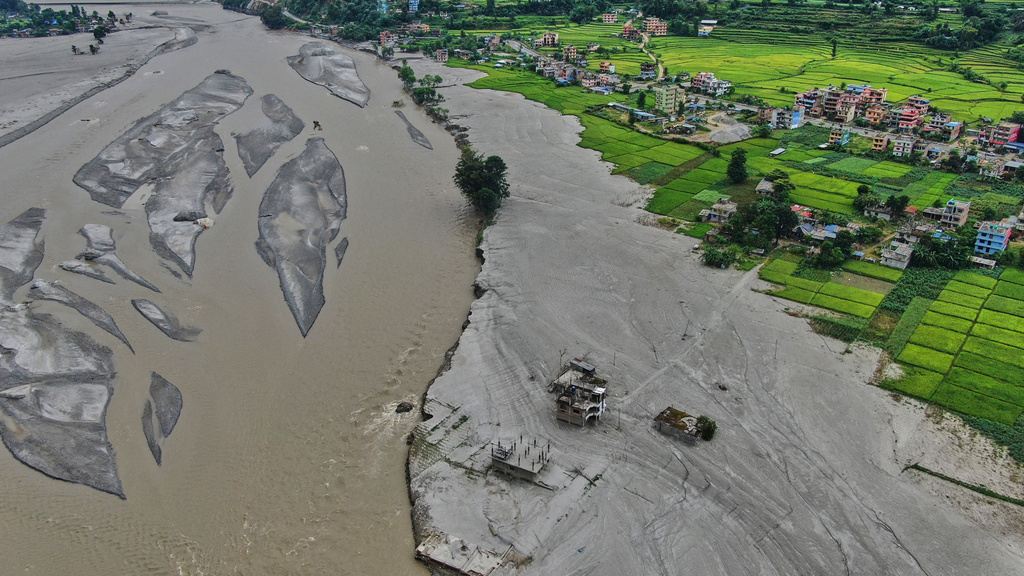 Farmland covered in mud and houses damaged by flash floods are seen along the banks of the Trishuli River in Galchi, in Nepal's Nuwakot district, Wednesday, Sept. 23, 2026. (AP Photo/Niranjan Shrestha)