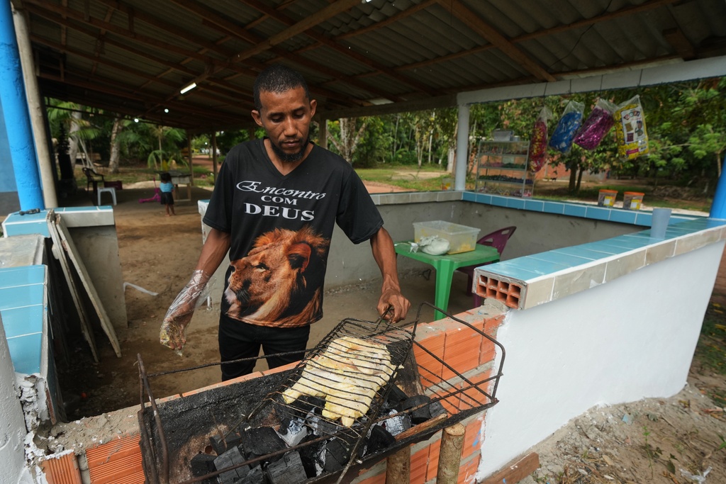 A man cooks chicken in Itacoa Miri, Brazil, Tuesday, Nov. 18, 2025. (AP Photo/Fernando Llano)