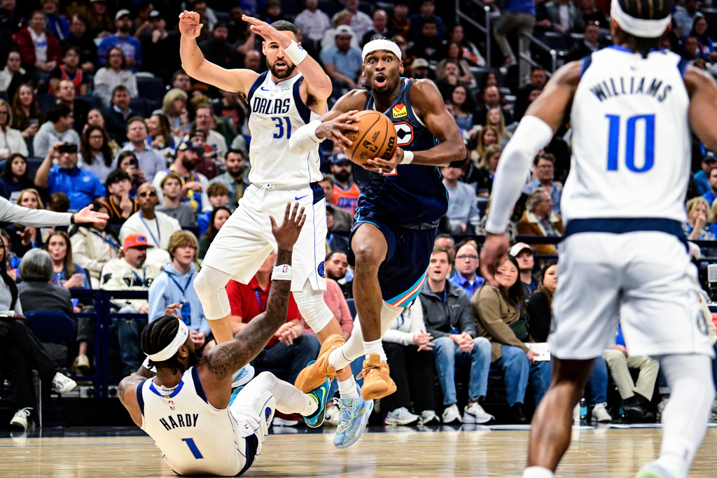 Oklahoma City Thunder guard Shai Gilgeous-Alexander (2) drives over Dallas Mavericks guard Jaden Hardy (1) during the second half of an NBA basketball game, Friday, Dec. 5, 2025, in Oklahoma City. (AP Photo/Gerald Leong)