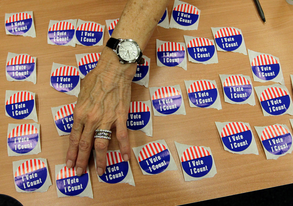 FILE - An election judge arranges "I Vote, I Count" stickers on a table in the Marion County Clerks office as voters cast early ballots in Indianapolis, Oct. 22, 2012. (AP Photo/Michael Conroy, File)