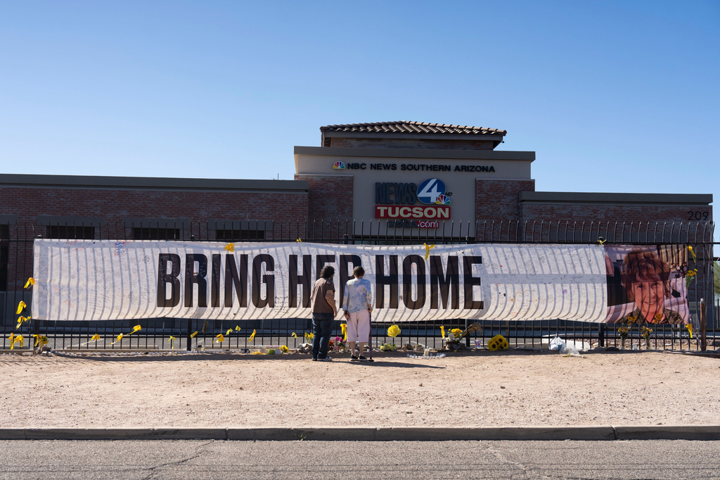FILE - People visit a banner for Nancy Guthrie, the missing mother of "Today" show host Savannah Guthrie, outside the KVOA Newsroom in Tucson, Ariz., on March 6, 2026. (AP Photo/Rebecca Noble, File)