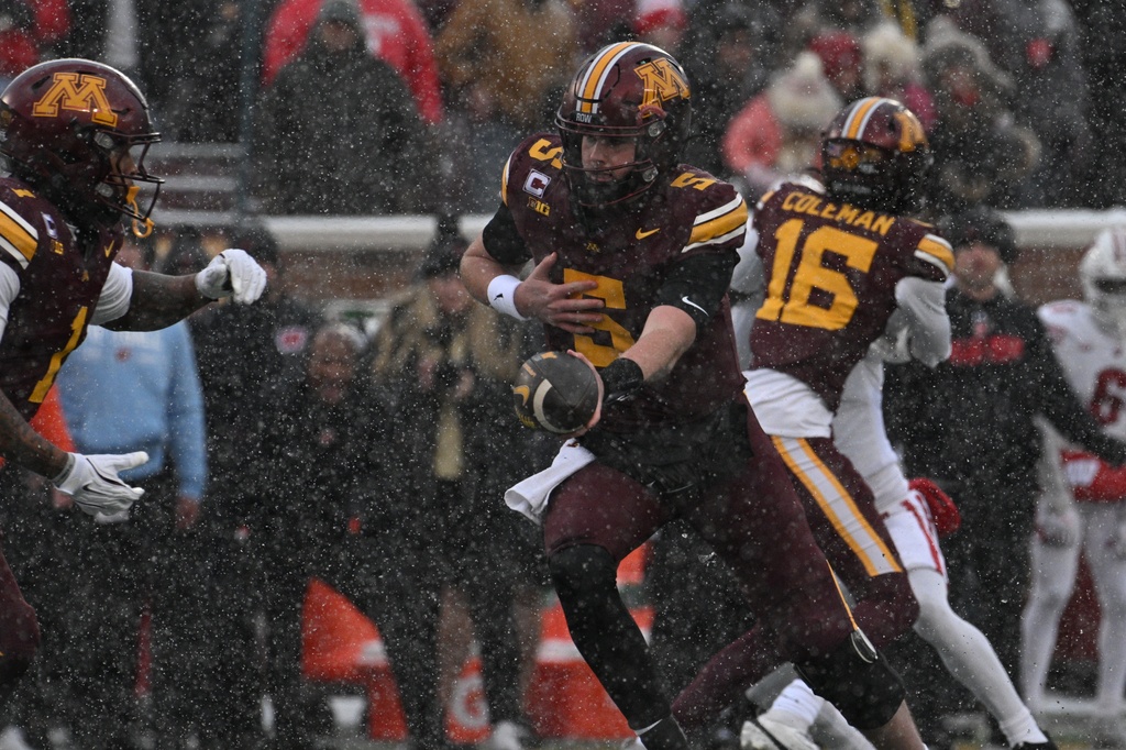 Minnesota quarterback Drake Lindsey hands off the ball to running back Darius Taylor during the first half of an NCAA college football game against Wisconsin, Saturday, Nov. 29, 2025, in Minneapolis. (AP Photo/Tom Baker)