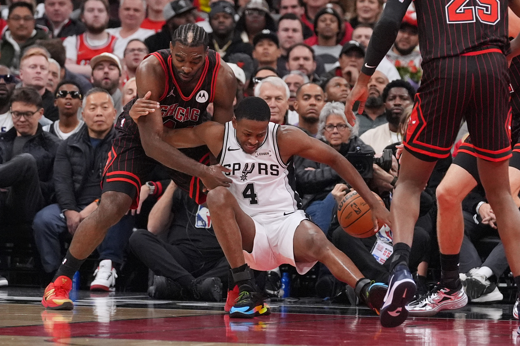 San Antonio Spurs guard De'Aaron Fox (4) battles for a loose ball against Chicago Bulls forward Patrick Williams during the first half of an NBA basketball game in Chicago, Monday, Nov. 10, 2025. (AP Photo/Nam Y. Huh)