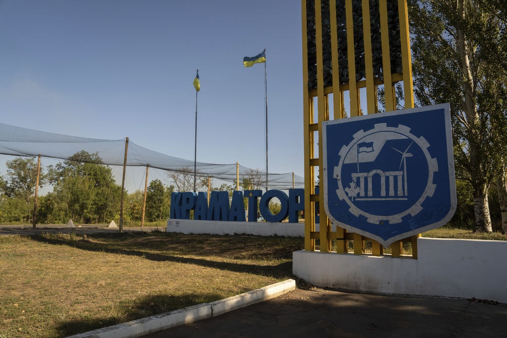 The Kramatorsk city sign and Ukrainian flags are seen next to the road covered with nets to protect cars from the enemy drones, Kramatorsk, Donetsk region, Ukraine, Friday, Sept.12, 2025. (AP Photo/Alex Babenko)