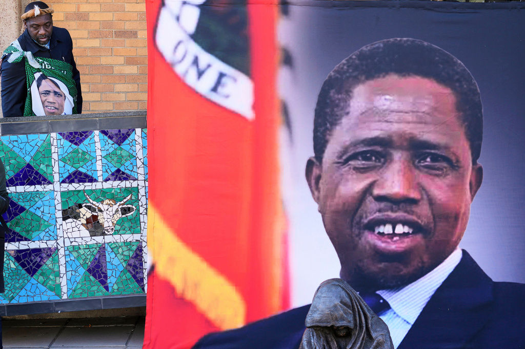 FILE -A supporter arrives for a Mass for former Zambian President Edgar Lungu, shown in a banner at right, at the Cathedral of Christ the King in Johannesburg, South Africa, June 25, 2025. (AP Photo/Themba Hadebe, File)