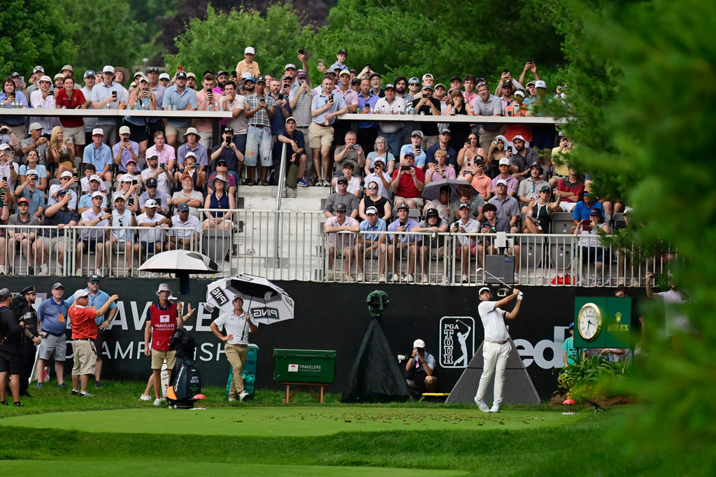Scottie Scheffler, right, tees off the eighth hole during the third round of the Travelers Championship golf tournament at TPC River Highlands, Saturday, June 27, 2026, in Cromwell, Conn. (AP Photo/Jessica Hill)