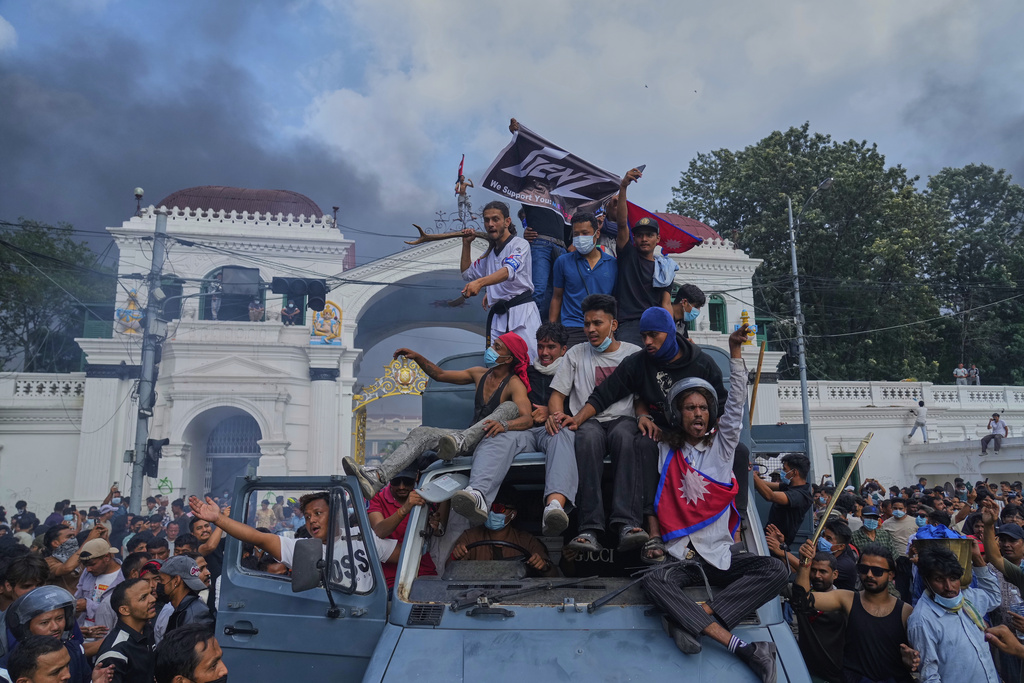 Protesters celebrate at the Singha Durbar, the seat of Nepal's government's various ministries and offices, after burning it down during a protest against a social media ban and corruption in Kathmandu, Nepal, Tuesday, Sept. 9, 2025. (AP Photo/Niranjan Shrestha)