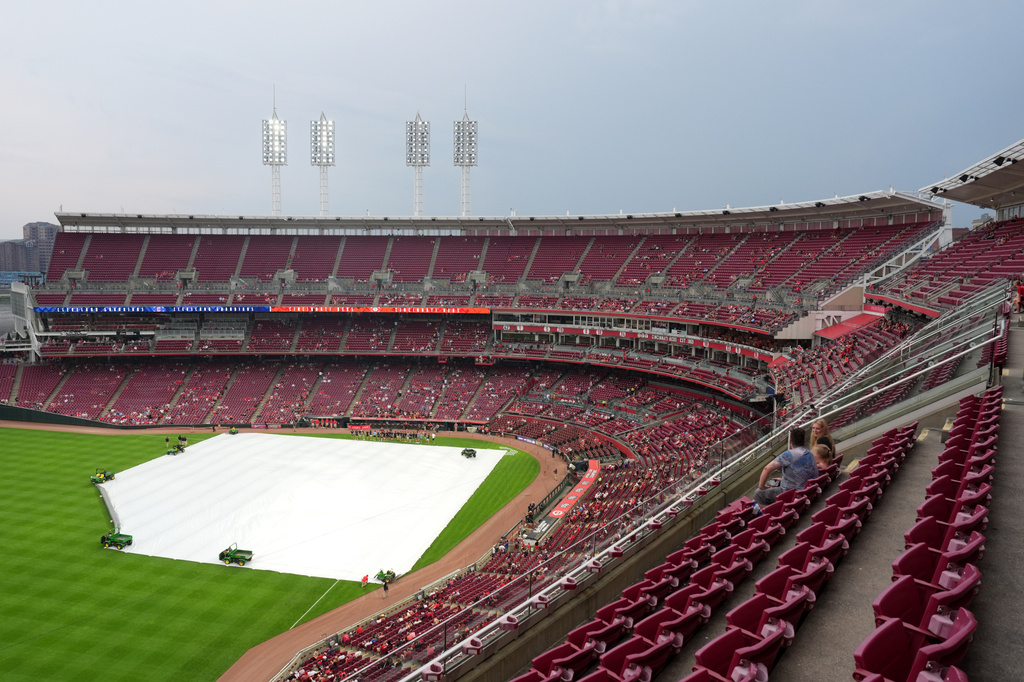 The infield is covered during a rain delay before a baseball game between the Cleveland Guardians and the Cincinnati Reds, Monday, July 27, 2026, in Cincinnati. (AP Photo/Kareem Elgazzar)