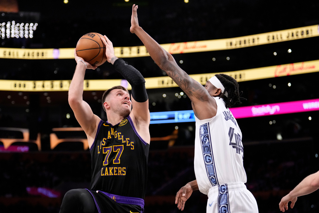 Los Angeles Lakers guard Luka Doncic, left, shoots as Memphis Grizzlies forward GG Jackson defends during the second half of an NBA basketball game Friday, Jan. 2, 2026, in Los Angeles. (AP Photo/Mark J. Terrill)
