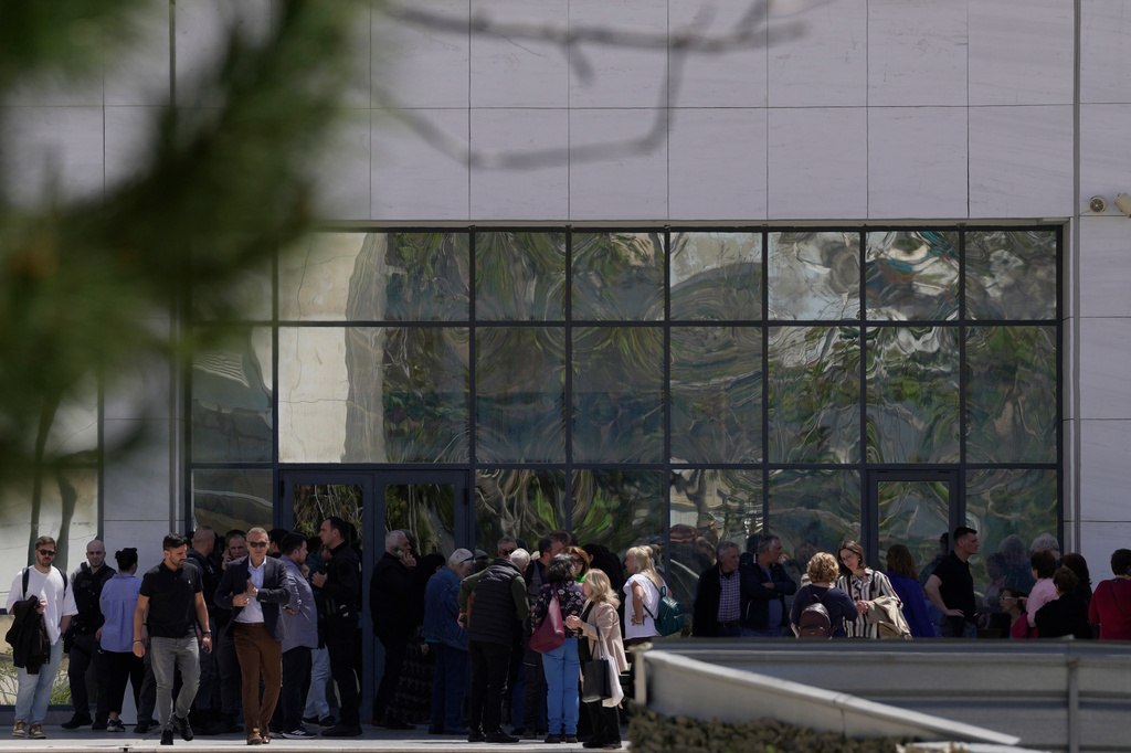People gather outside a courthouse after a gunman opened fire leaving several people wounded in Athens, Tuesday, April 28, 2026. (AP Photo/Petros Giannakouris)