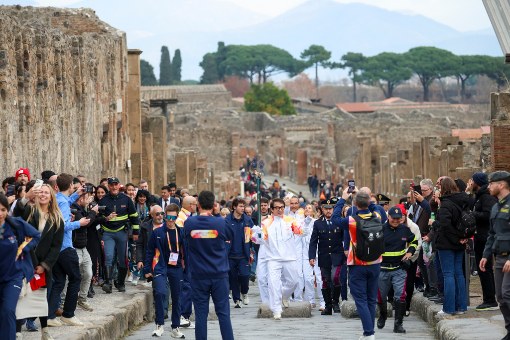 Actor Jackie Chan holds the olympic torch passing through the Archaeological Park in Pompeii, Italy, Monday, Dec. 22, 2025. (Alessandro Garofalo/LaPresse via AP)