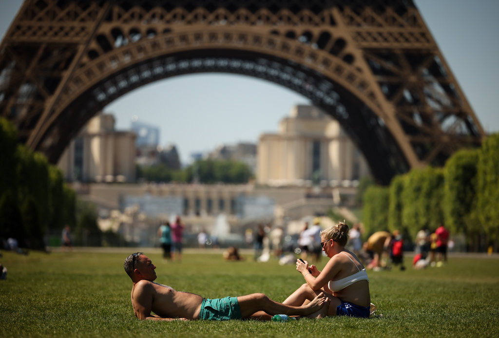 FILE - People enjoy the sun next to the Eiffel Tower in Paris, May 27, 2026. (AP Photo/Thomas Padilla, File)