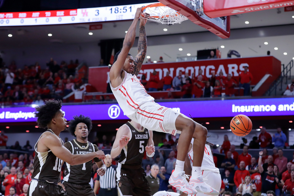 Houston center Chris Cenac Jr., center, hangs on the rim after dunking against Lehigh during the first half of an NCAA college basketball game, Monday, Nov. 3, 2025, in Houston. (AP Photo/Michael Wyke)