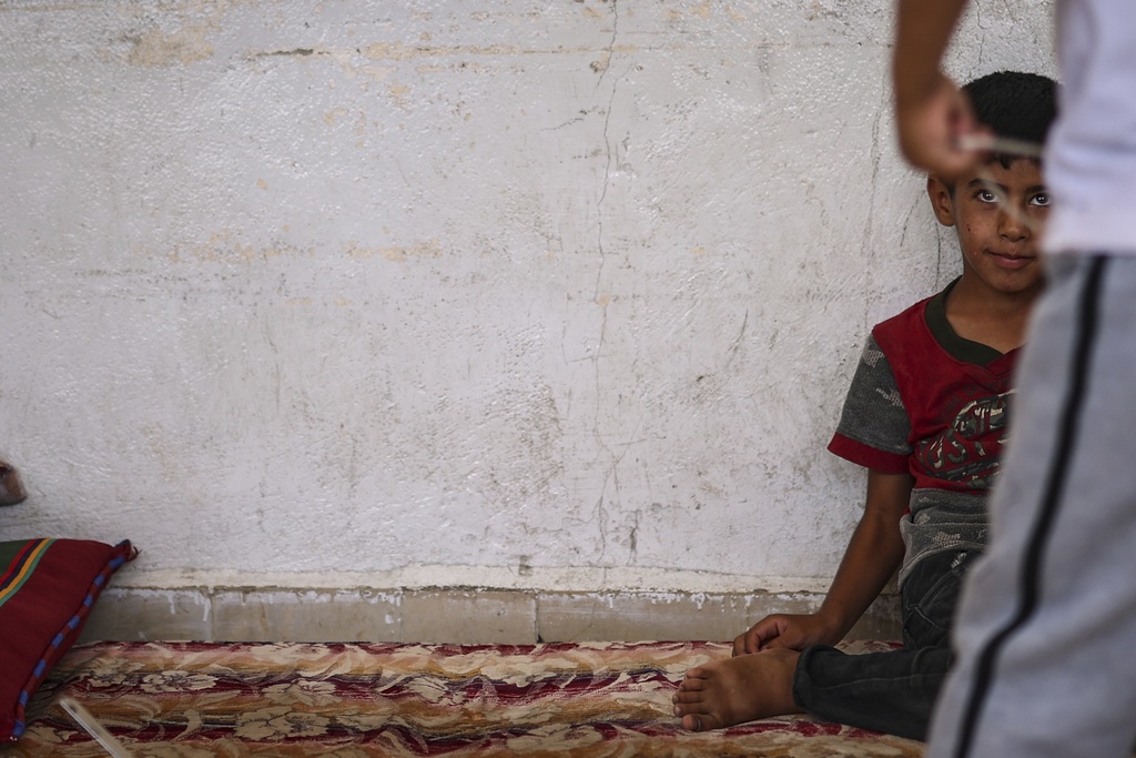 A Bedouin boy watches as other children play at a school sheltering displaced Syrian Bedouins from the Sweida region, who were forced from their homes after clashes between Druze militias and Bedouin groups, in the village of Abtaa in rural Daraa, Syria, Friday, Aug. 15, 2025. (AP Photo/Ghaith Alsayed)
