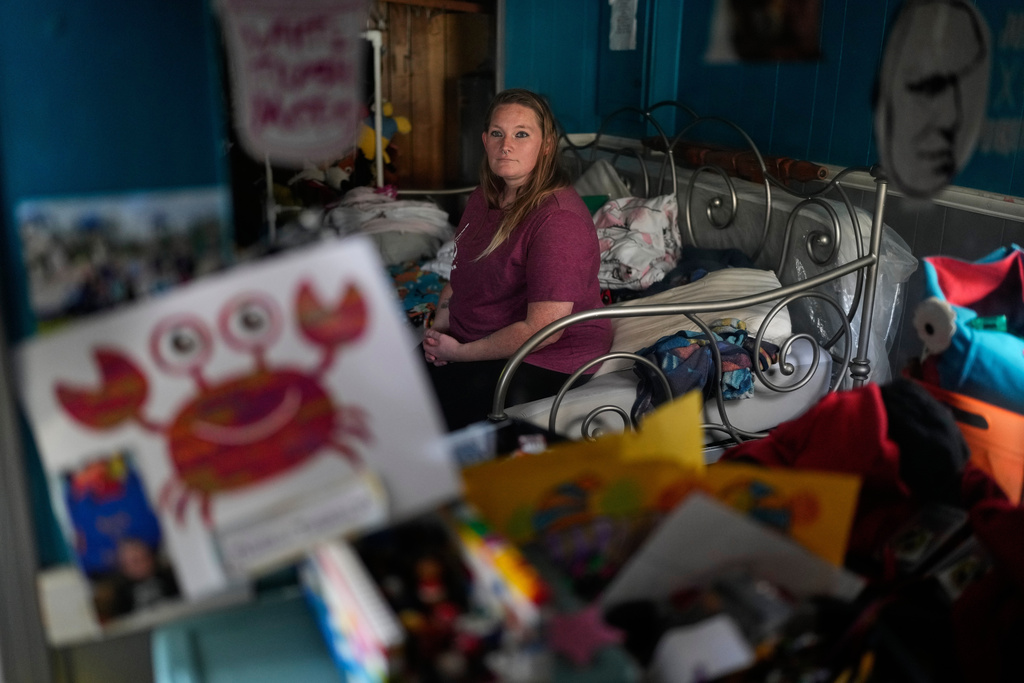 Dianna Tompkins looks at a mirror while she sits on a bed at her home in Demotte, Ind., Dec. 17, 2025. (AP Photo/Nam Y. Huh)