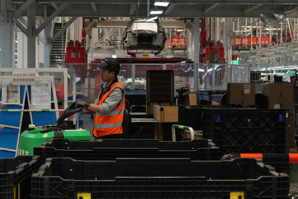A worker transfers compartments at the Tesla Model Y production lines at the Tesla Gigafactory assembly plant during a media organized tour, in Shanghai, China, Tuesday, April 14, 2026. (AP Photo/Andy Wong)