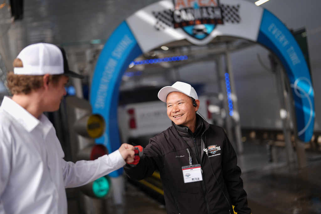 Mayflower Church Deacon Luo Changcheng, wearing a tag with the American name Peter, gets a fist bump from his boss, Eric Smith, as he works at a car wash in Midland, Texas, Jan. 20, 2025. (AP Photo/Rebecca Blackwell)