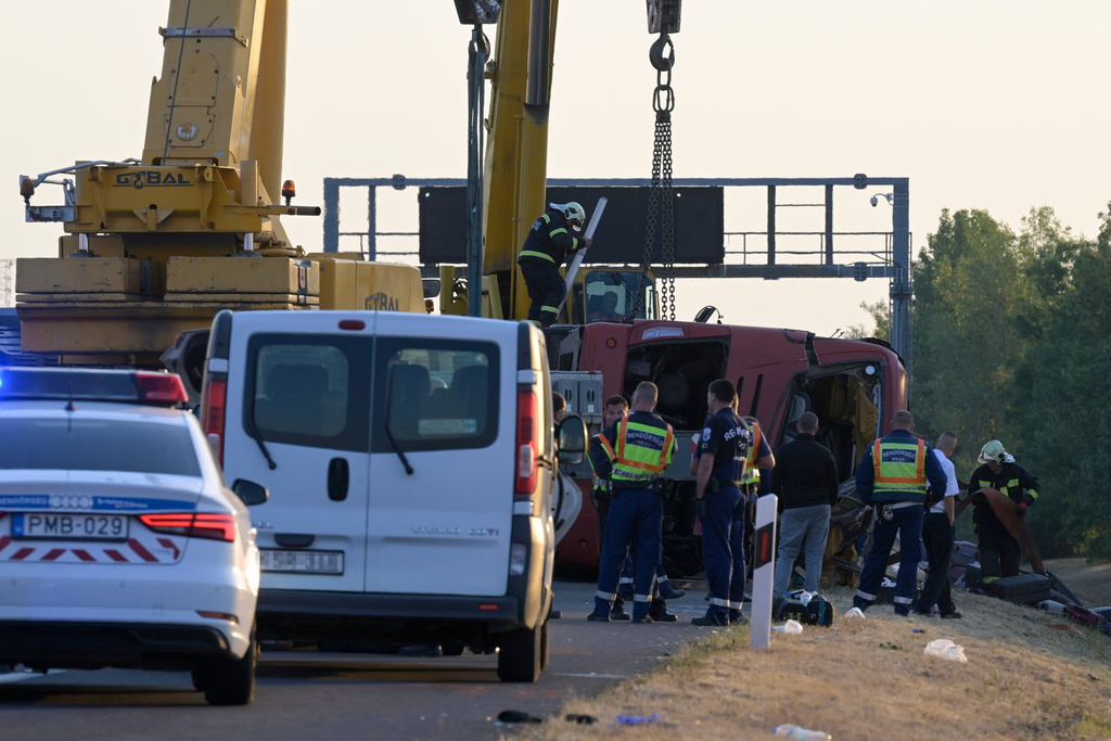 Emergency services attend the scene after a passenger bus went off the road and overturned in a ditch along a highway between Mezokeresztes and Mezonagymihaly in Hungary, Sunday, Aug. 16, 2026. (Zoltan Mathe/MTI via AP)