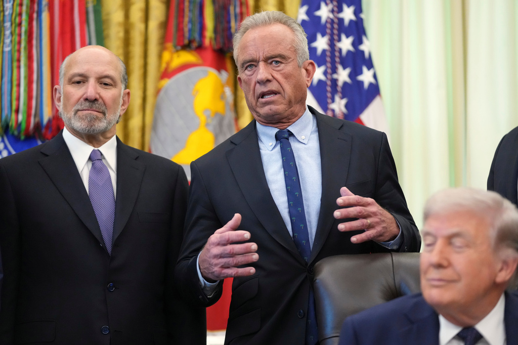 Health and Human Services Secretary Robert F. Kennedy Jr. speaks as President Donald Trump and Commerce Secretary Howard Lutnick listen during an event on health care affordability in the Oval Office at the White House, Thursday, April 23, 2026, in Washington. (AP Photo/Mark Schiefelbein)