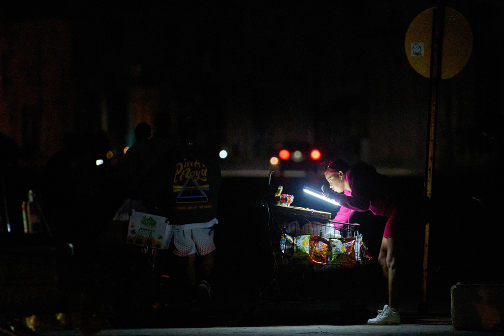 A vendor lights her way with a battery-powered lamp while waiting for customers on the Malecón during a blackout in Havana, Cuba, Saturday, March 21, 2026. (AP Photo/Ramon Espinosa)