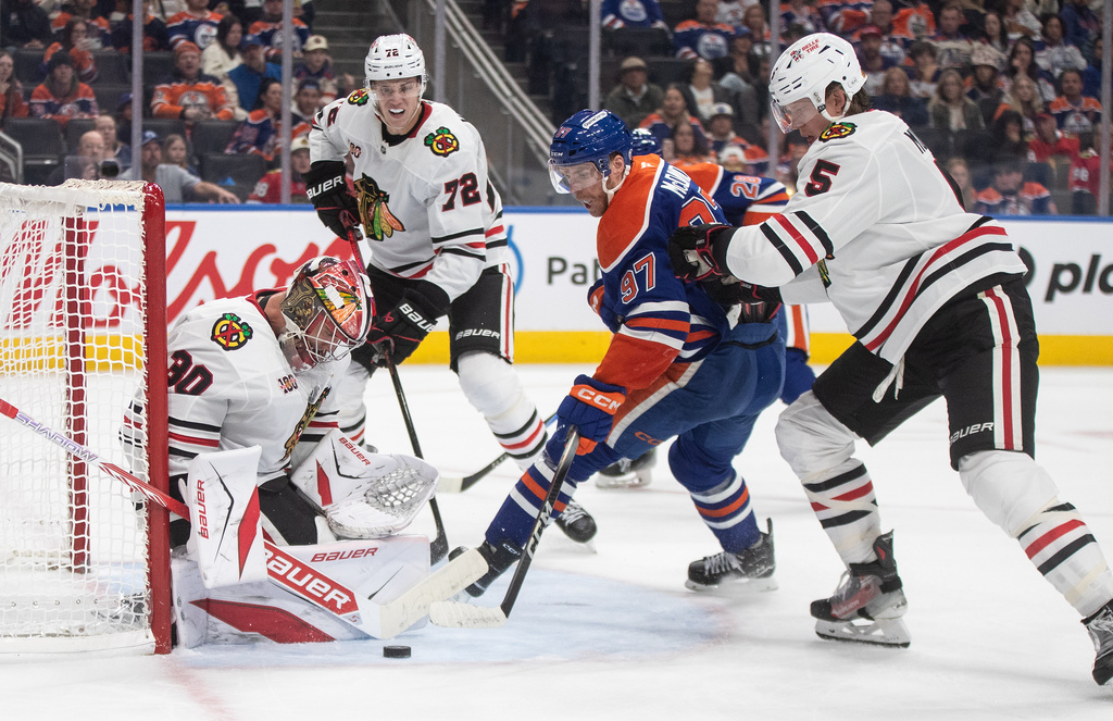 Chicago Blackhawks goalie Spencer Knight (30) makes a save on Edmonton Oilers' Connor McDavid (97) as Connor Murphy (5) defends and Alex Vlasic (72) looks for the rebound during second period NHL action, in Edmonton on Saturday, Nov. 1, 2025. (Jason Franson/The Canadian Press via AP)