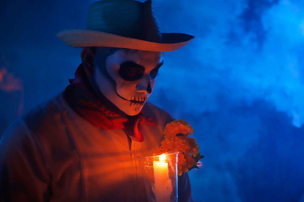 A man with skull make up holds a candle during the Paseo de las Animas parade as part of the Day of the Dead celebrations in Merida, Mexico, Friday, Oct. 31, 2025. (AP Photo/Martin Zetina)