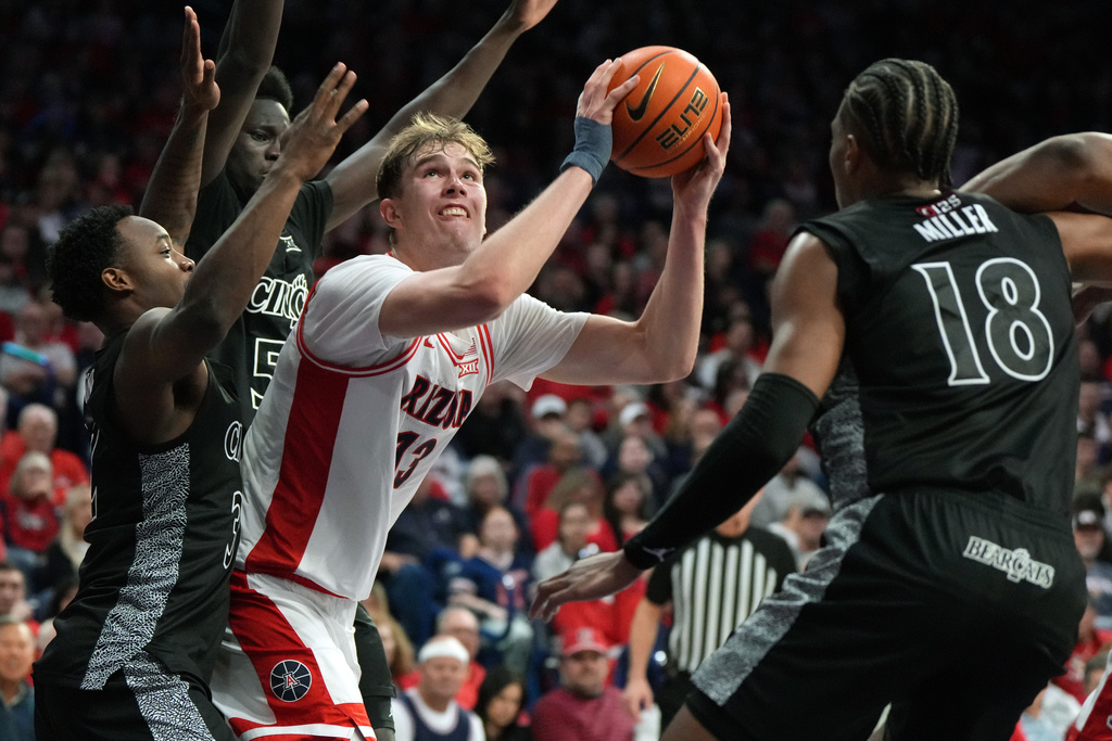 Arizona center Motiejus Krivas scores in between Cincinnati guard Grant Darbyshire (13), guard Sencire Harris (5), and forward Baba Miller during the second half of an NCAA college basketball game, Wednesday, Jan. 21, 2026, in Tucson, Ariz. (AP Photo/Rick Scuteri)