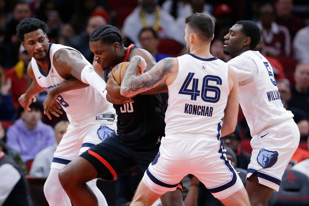 Houston Rockets center Clint Capela, second from left, tries to get past Memphis Grizzlies forward Jaren Jackson Jr. (8), guard John Konchar (46) and guard Vince Williams Jr. (5) who try to strip the ball away from him during the first half of an NBA basketball game Monday, Jan. 26, 2026, in Houston. (AP Photo/Michael Wyke)