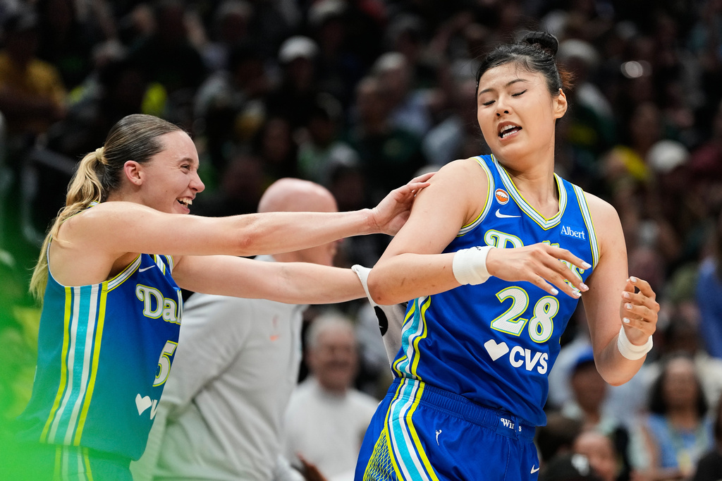 Dallas Wings guard Paige Bueckers, left, smiles while pushing center Li Yueru (28) after she made a basket against the Seattle Storm during the second half of a WNBA basketball game, Monday, June 22, 2026, in Seattle. (AP Photo/Lindsey Wasson)