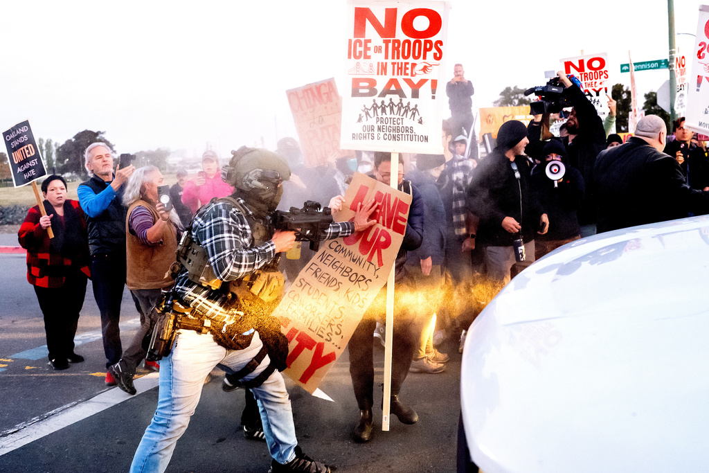 A person pushes a protester blocking a caravan of U.S. Customs and Border Protection personnel trying to enter Coast Guard Base Alameda on Thursday, Oct. 23, 2025, in Oakland, Calif. (AP Photo/Noah Berger)
