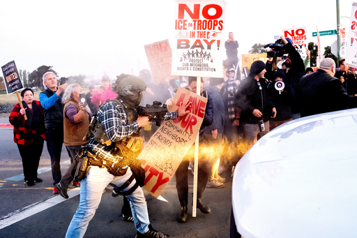 A person pushes a protester blocking a caravan of U.S. Customs and Border Protection personnel trying to enter Coast Guard Base Alameda on Thursday, Oct. 23, 2025, in Oakland, Calif. (AP Photo/Noah Berger) A person pushes a protester blocking a caravan of U.S. Customs and Border Protection personnel trying to enter Coast Guard Base Alameda on Thursday, Oct. 23, 2025, in Oakland, Calif. (AP Photo/Noah Berger)