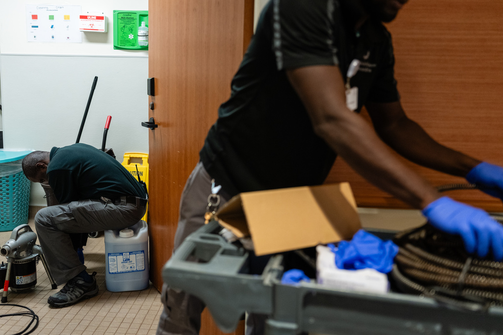 Maintenance worker Eric Frimpong, left, originally from Ghana, prepares a drainage hole, while his coworker, Melvin Palmer, right, originally from Sierra Leone, grabs a metal cleaning cable at Goodwin House Alexandria, Thursday, Oct. 16, 2025, in Alexandria, Va. (AP Photo/Eric Lee)