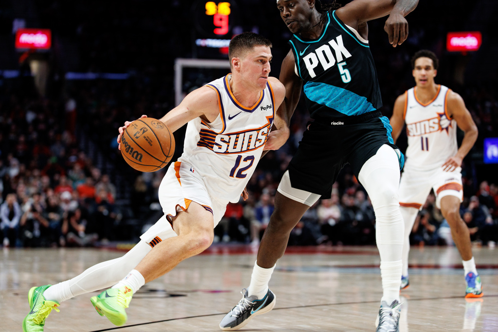 Phoenix Suns guard Collin Gillespie, left, dribbles against Portland Trail Blazers guard Jrue Holiday, right, during the first half of an NBA basketball game Tuesday, Feb. 3, 2026, in Portland, Ore. (AP Photo/Howard Lao)