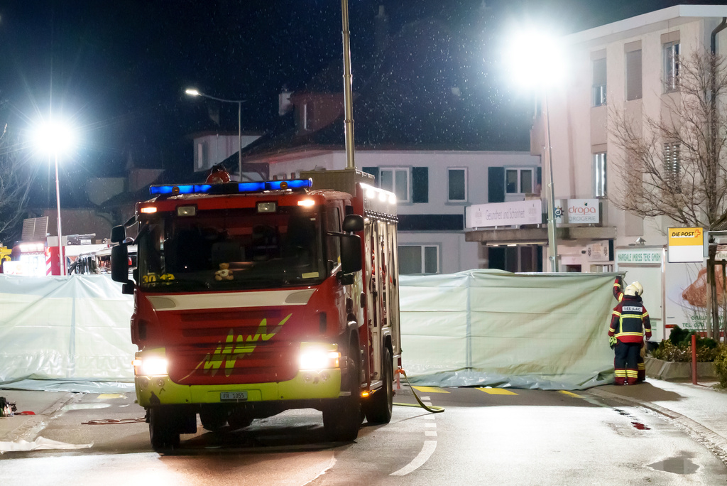Firefighters and police officers install barriers to secure the area where a postal bus caught fire in Kerzers, Switzerland, Tuesday, March 10, 2026, after several passengers were killed and others injured when a postal bus caught fire late Tuesday afternoon in the center of Kerzers, according to the Fribourg canton police. (Laurent Merlet/Keystone via AP)
