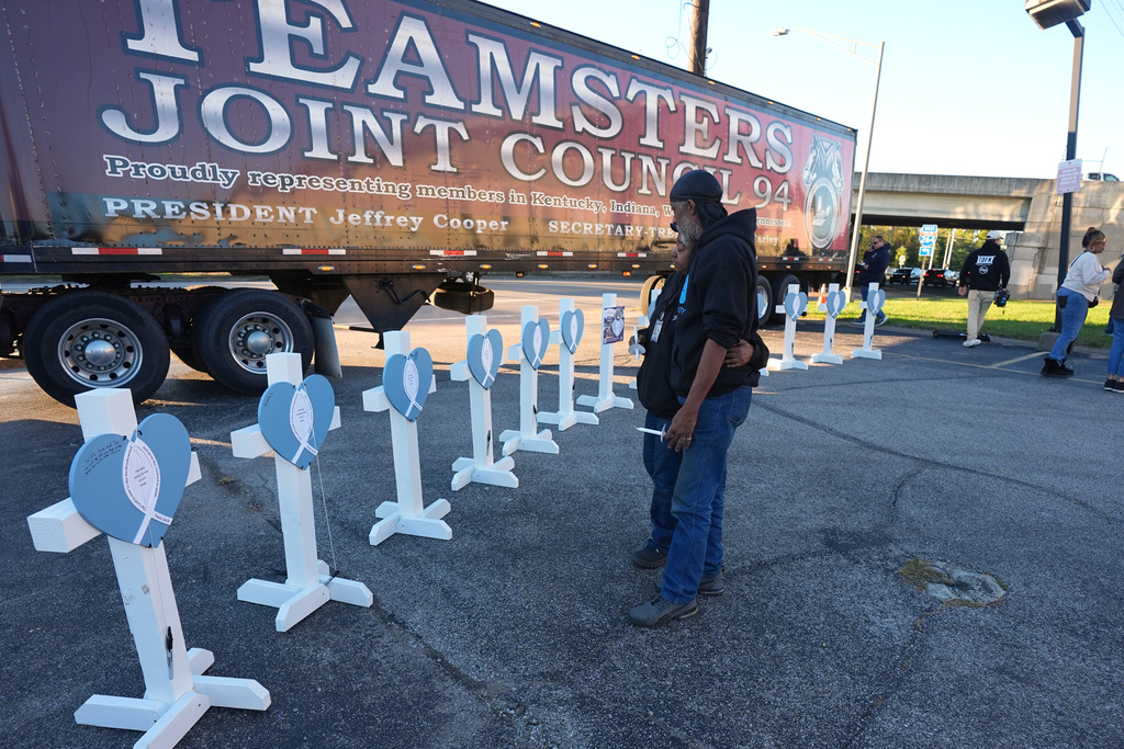 Allen Wilson, right, hugs an attendee after they wrote on crosses for victims during a vigil Thursday, Nov. 6, 2025, in Louisville, Ky., after a UPS plane crashed at Louisville Muhammad Ali International Airport. (AP Photo/Darron Cummings)