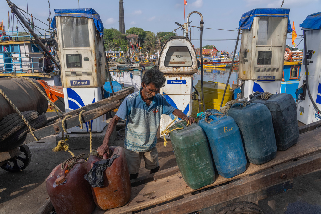 A deckhand arranges empty fuel cans on his handcart at Sassoon Dock beside a cooperative diesel pump that is shut due to rising bulk fuel prices in Mumbai, India, Tuesday, April 7, 2026. (AP Photo/Rafiq Maqbool)