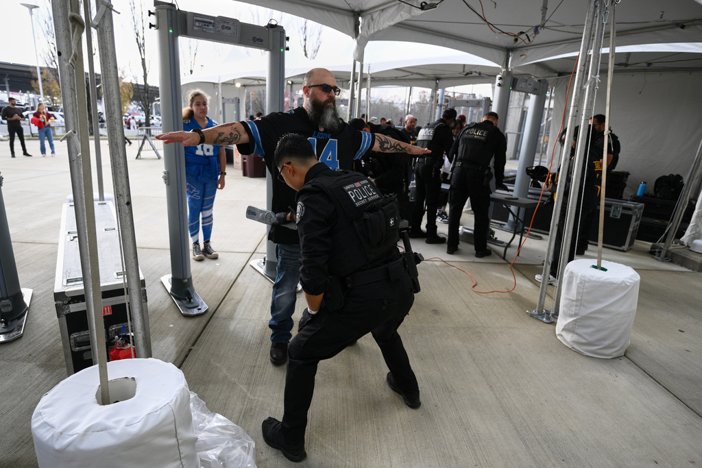 Fans enter through a security checkpoint before an NFL football game between the Washington Commanders and the Detroit Lions Sunday, Nov. 9, 2025, in Landover, Md. (AP Photo/Nick Wass)
