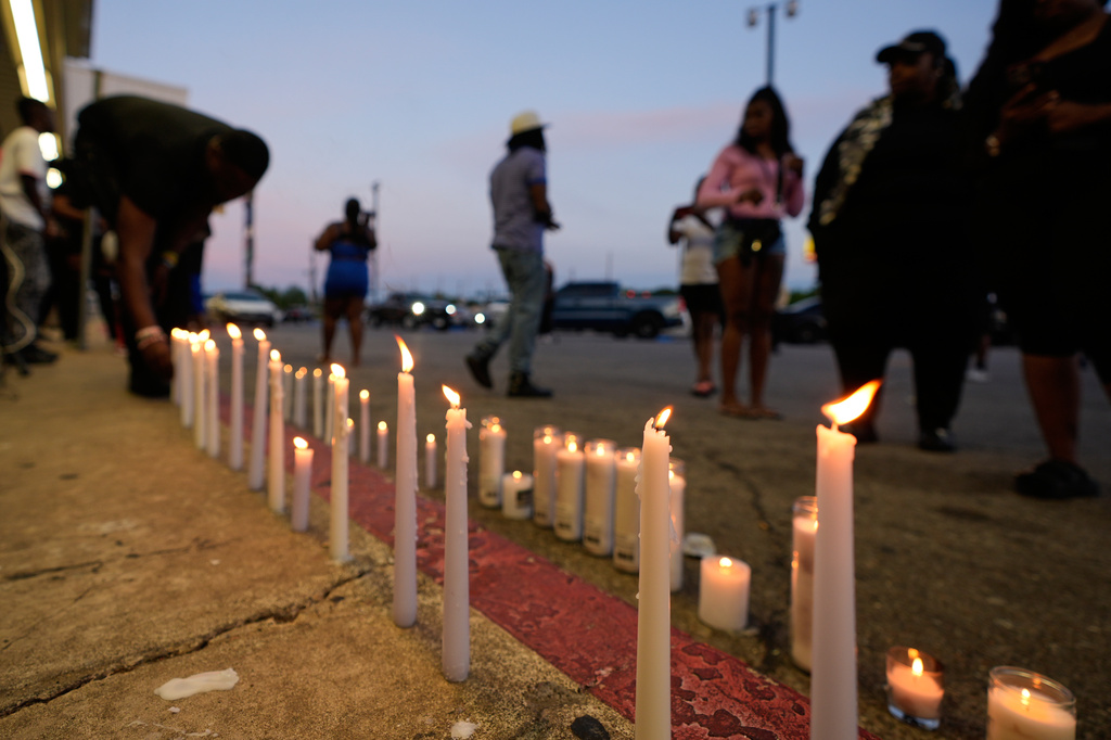 A man lights a candle during a prayer vigil for the victims of a mass shooting earlier in the day, Sunday, April 19, 2026, in Shreveport, La. (AP Photo/Gerald Herbert)