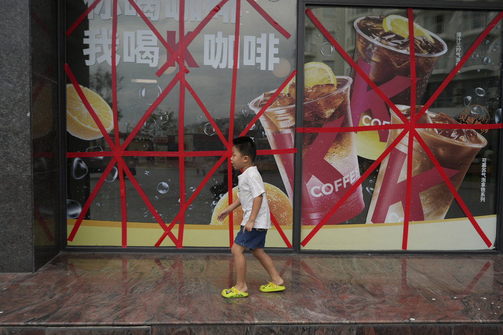 A child passes by a restaurant with its glass windows taped protectively against strong winds ahead of Super Typhoon Ragasa in Shenzhen in southern China's Guangdong province on Tuesday, Sept. 23, 2025. (AP Photo/Ng Han Guan)