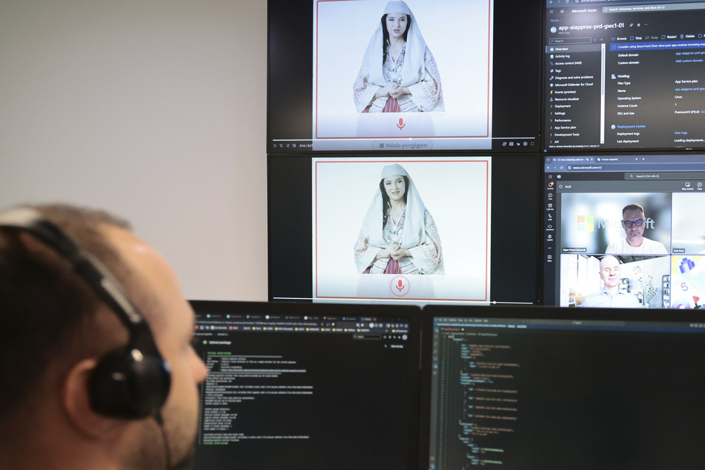 An Albanian expert works at the National Agency for Information Society as an artificial intelligence "minister" Diella, whose name means "Sun" in Albanian, is seen on the screens in Tirana, Albania, Friday, Sept. 12, 2025. (AP Photo/Vlasov Sulaj)