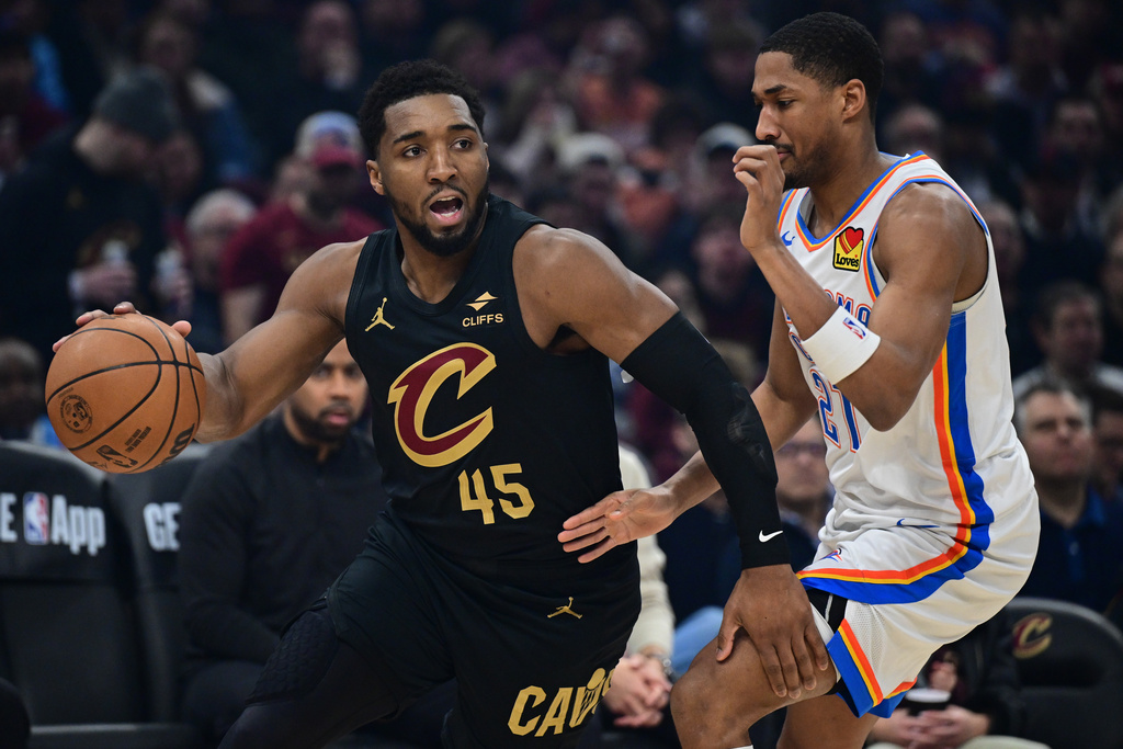 Cleveland Cavaliers guard Donovan Mitchell (45) drives against Oklahoma City Thunder guard Aaron Wiggins, right, in the first half of an NBA basketball game, Monday, Jan. 19, 2026, in Cleveland. (AP Photo/David Dermer)