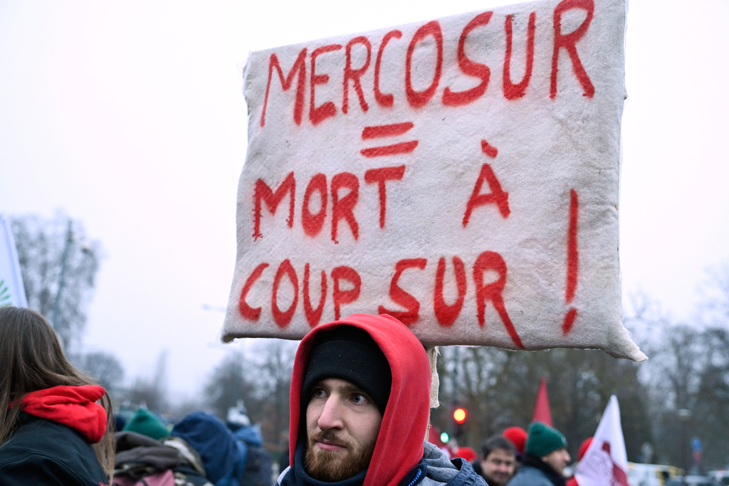 A man holds up a sign which reads "Mercosur equals death for sure" as he participates in a demonstration against the EU-Mercusor trade agreement, outside the European Parliament in Strasbourg, eastern France, Tuesday, Jan. 20, 2026. (AP Photo/Pascal Bastien)
