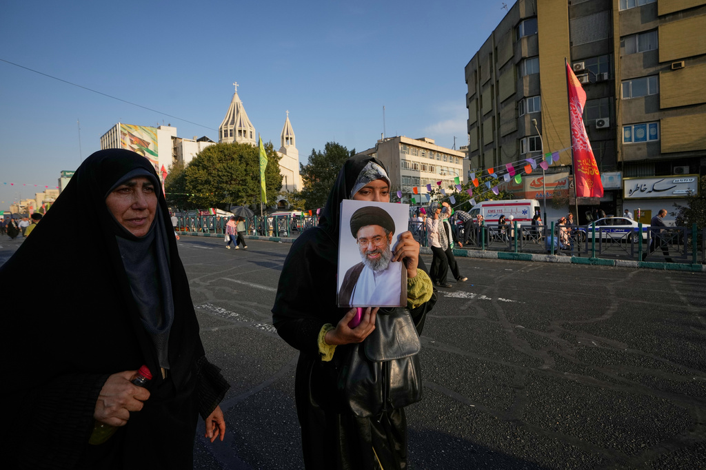 A government supporter holds a portrait of Iran's Supreme Leader Mojtaba Khamenei during a street celebration marking Prophet Muhammad's birthday, with St. Sarkis Armenian Cathedral in the background, in Tehran, Iran, Sunday, Aug. 30, 2026. (AP Photo/Vahid Salemi)