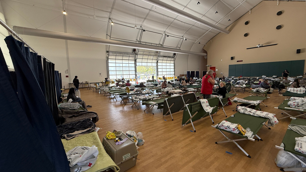 This image provided by American Red Cross Southern California Region, people arrive at Freedom Hall, an evacuation center in Fountain Valley, Calif., after a storage tank containing a chemical used to make plastic parts overheated Thursday at an aerospace plastics facility in Garden Grove, on Saturday, May 23, 2026. (American Red Cross Southern California Region via AP)